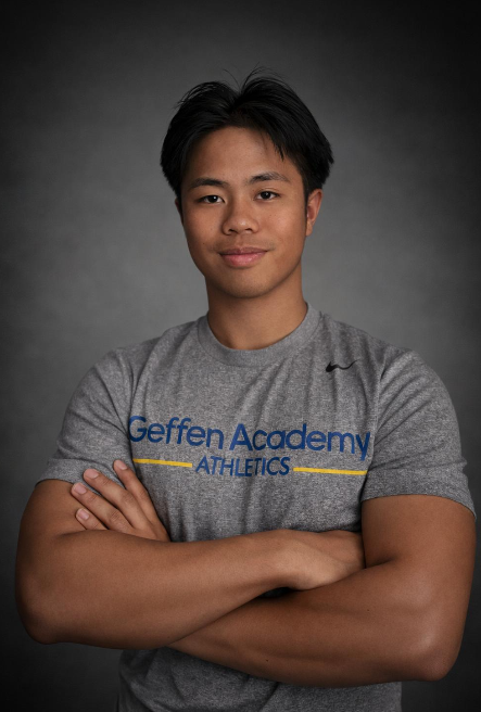 Man in Geffen Academy Athletics shirt smiling with arms crossed.